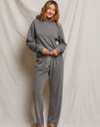 A person in a relaxed pose embodies effortless style in Perfectwhitetee's Collins Straight Sweatpant, paired with a gray hoodie. The cotton fleece set is complemented by black flip-flops, all against a neutral, draped fabric backdrop.