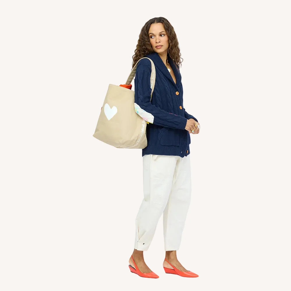 Kerri Rosenthal KR Imperfect Heart Hobo Tote carried by woman in blue cardigan and white pants, with red flats.