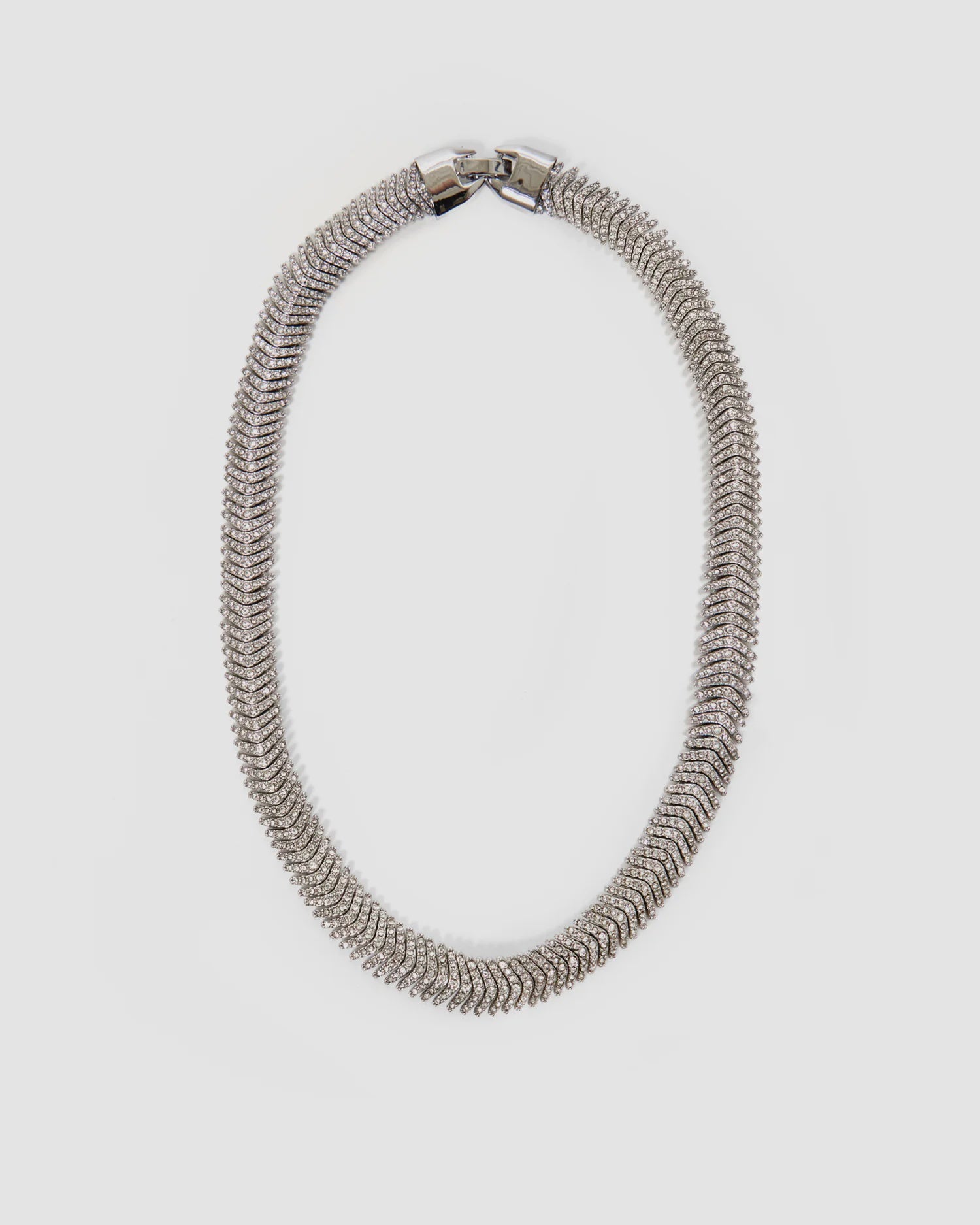 The Clare Vivier Herringbone Collar is a silver, textured rhodium-plated necklace with a sleek, rounded design and foldover clasp, shown on a plain white background.