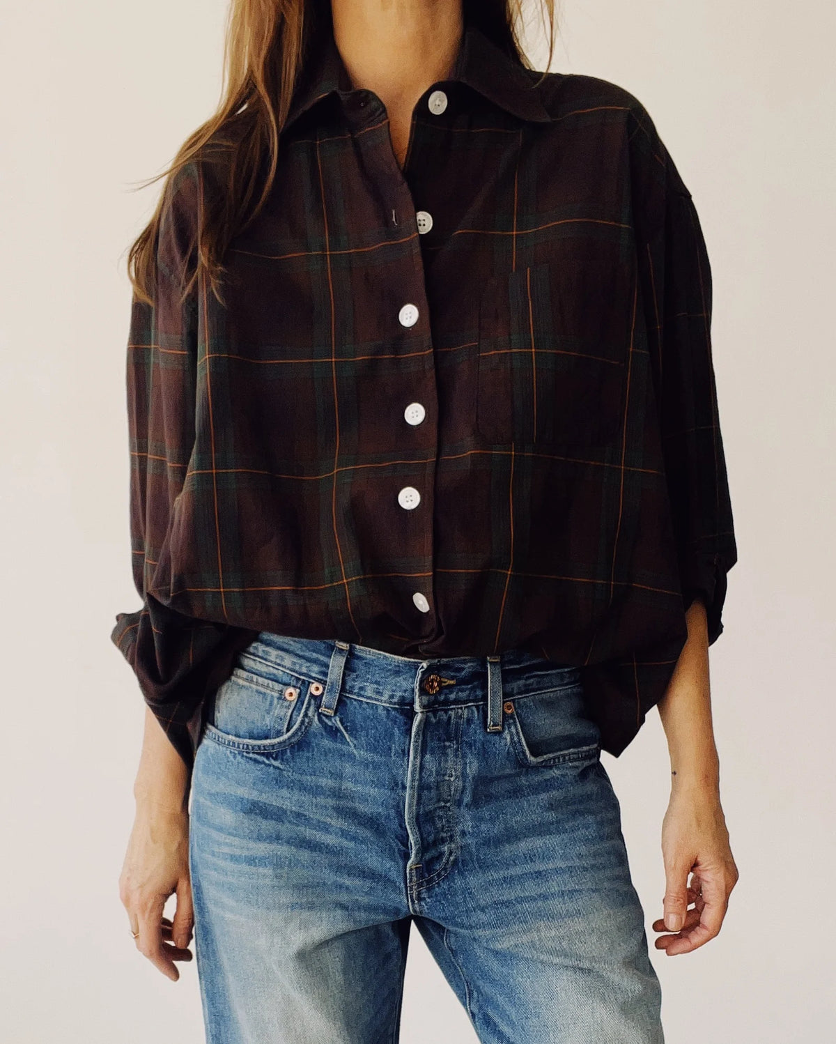 Brown plaid oversized shirt by Hey Gang paired with blue jeans, styled against a minimal light background.