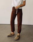 Hey Gang The Sweatpants in Cedar styled with a white shirt and tan clogs, shown on a concrete floor.