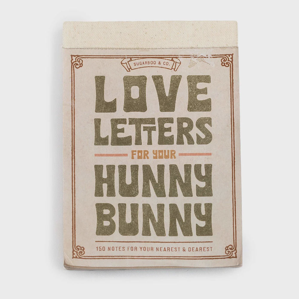 The 150 Love Letters for Your Hunny Bunny notepad by Sugarboo Designs has a beige cover with bold green and orange title text. It features perforated pages, a decorative border, and a charming "Sugarboo & Co." banner on top for sharing cherished notes.