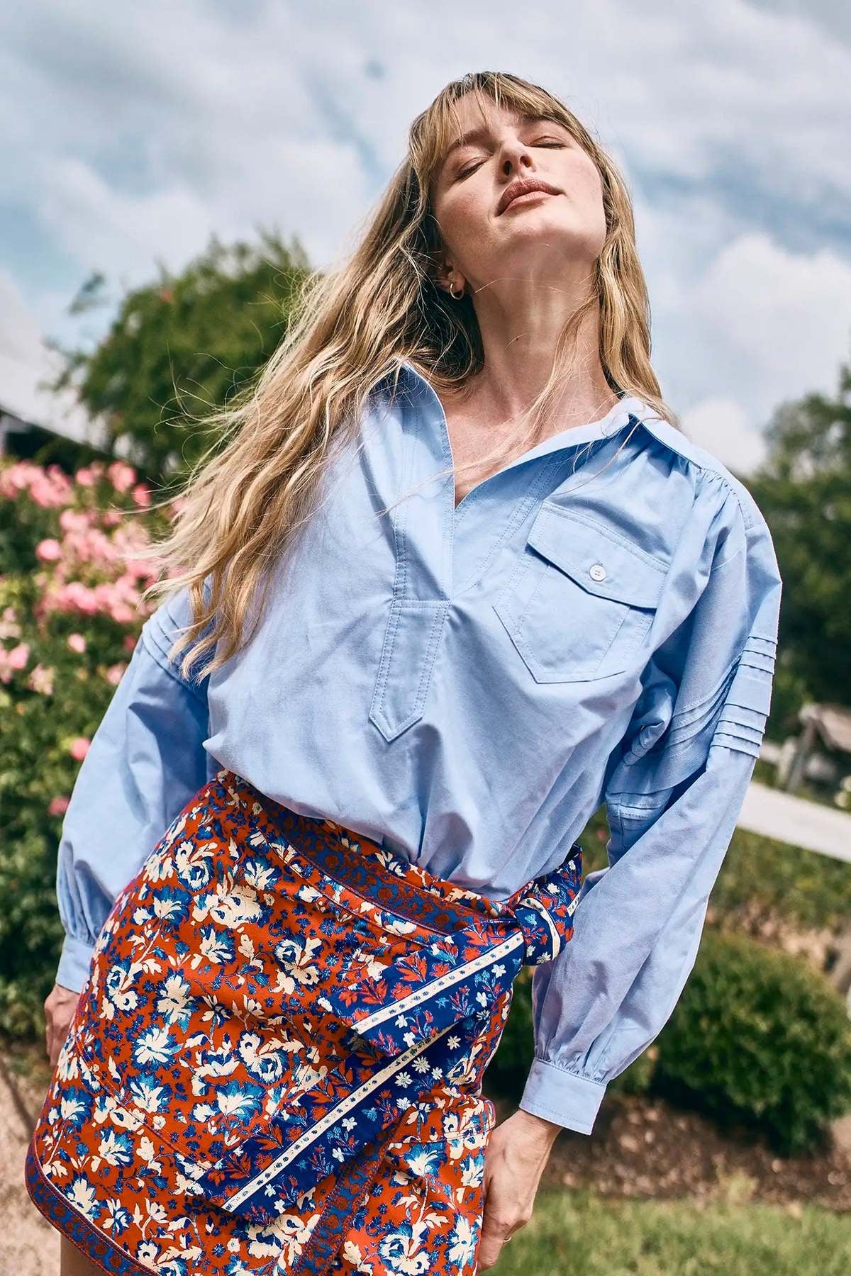 Evangeline blue oxford shirt and floral skirt by Hunter Bell NYC worn outdoors in a sunlit, relaxed lifestyle setting.