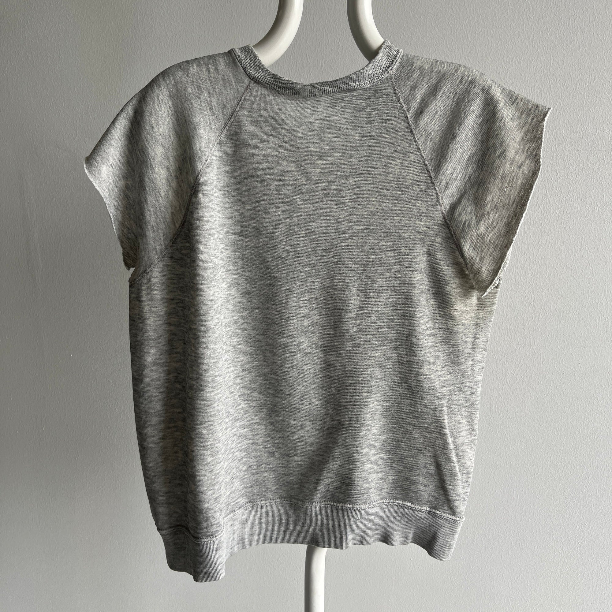 The product on display is a gray "80s USMC Short Sleeve Sweatshirt" by Red Vintage Co., showcased on a mannequin against a plain background. This shirt features raglan sleeves and offers a relaxed fit, crafted from soft fabric with a subtly distressed finish for an authentic vintage vibe.