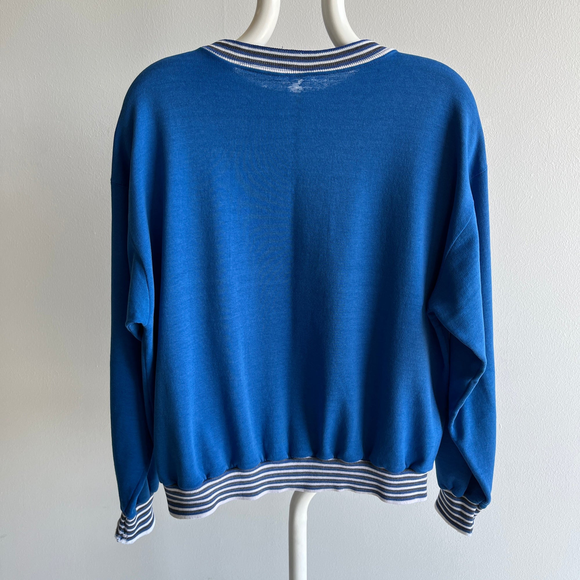 Modeled on a mannequin against a plain white backdrop, the 80s Mad Dog Ski Club Sweatshirt by Red Vintage Co. is a vintage blue long-sleeve garment featuring super cool cuffs with white and blue stripes. Its thinned out fabric ensures both comfort and style, making it an ideal choice for casual wear.