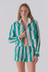 A woman models Cissa's The Boxer set—green and white vertical stripes in soft Egyptian cotton—with a partially unbuttoned shirt, standing against a plain backdrop.