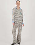 A person smiles, wearing the Me369 Bailey Track Pant with a matching button-up shirt featuring a gray abstract pattern, blue cuffs and collar, paired with black shoes, all set against a plain white background.