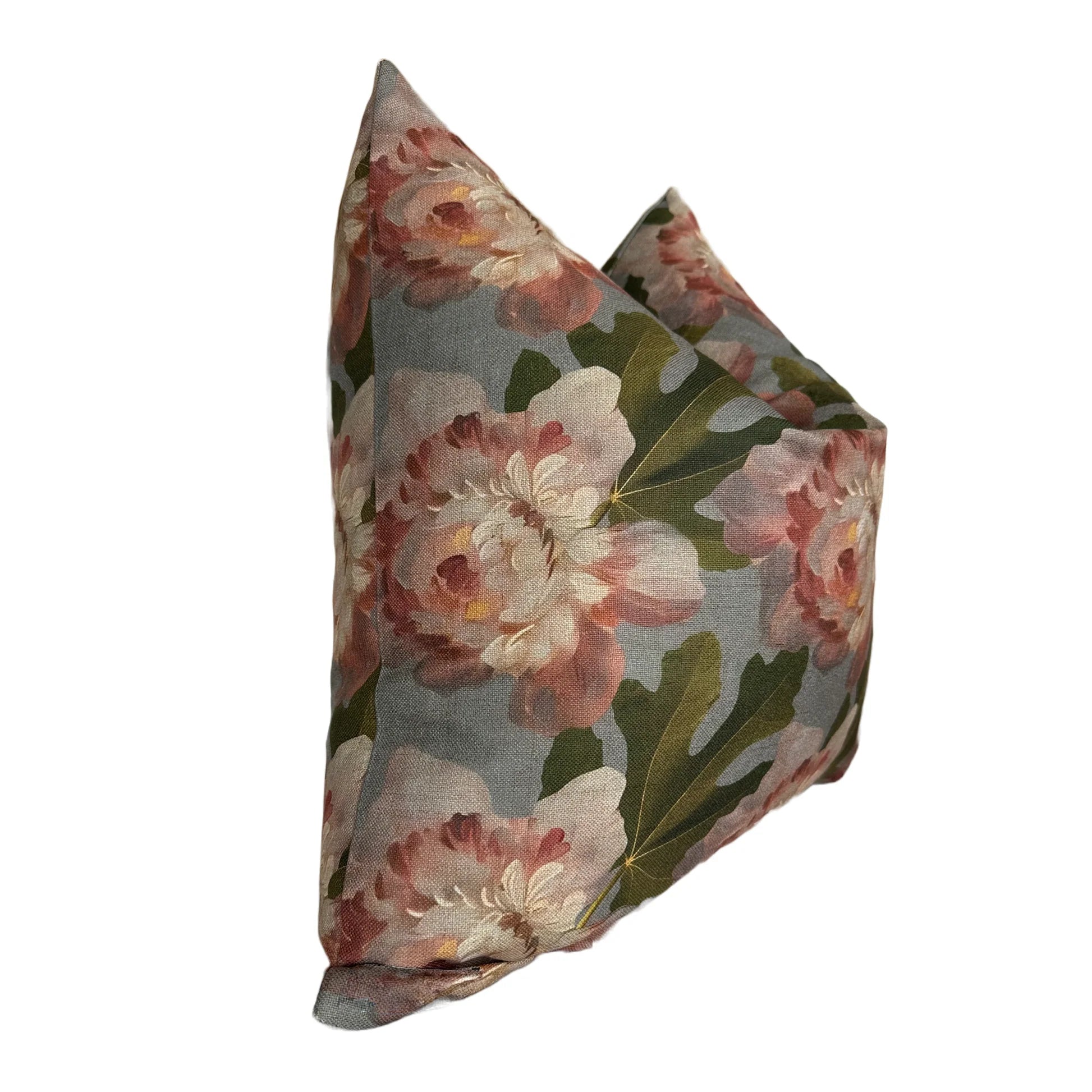 The Rennah Collective Iris Pillow 22x22 features a floral design with large pink and white flowers and green leaves on a muted gray polyester-linen cover, shown upright against a white background.