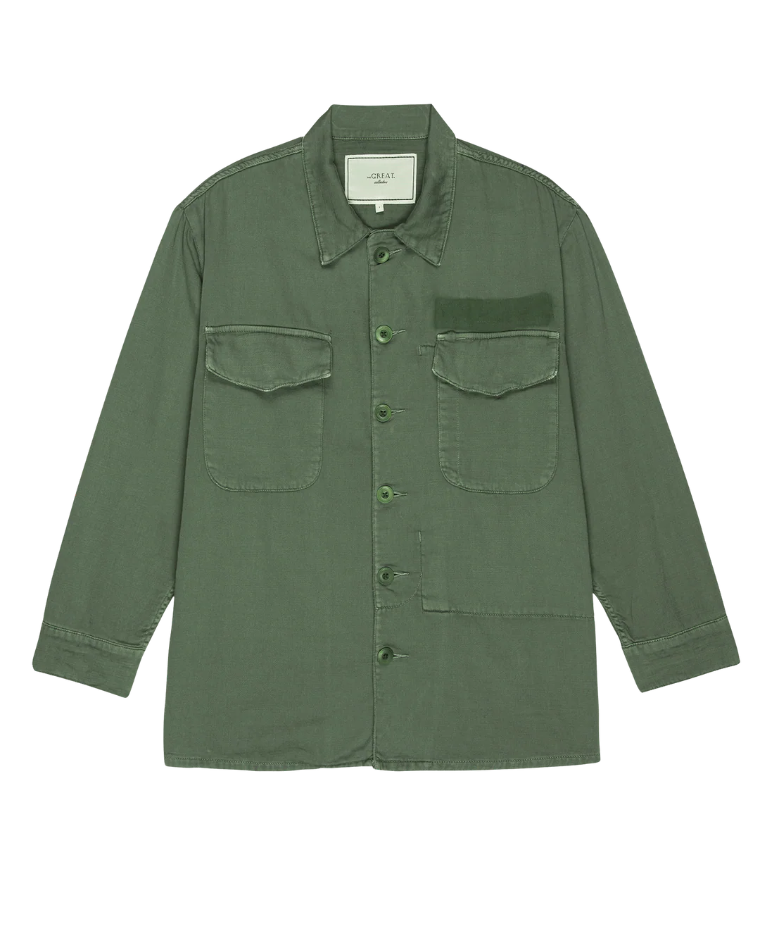 The Great Inc.’s The Vintage Army Jacket is an olive, long-sleeve cotton slub twill button-up with a collar, two chest pockets—one flapped and buttoned, one plain with a velvety patch—reminiscent of classic army style.