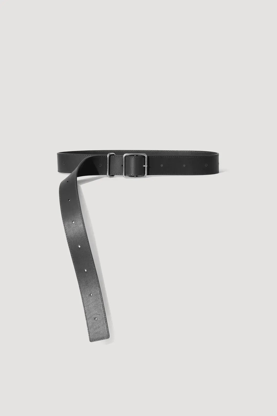 A sleek Janessa Leone Bowe Belt, crafted from regenerative leather, is displayed against a white background. The black belt showcases a metal buckle and an unfastened strap with adjustment holes, embodying the effortless style of Los Angeles.