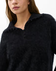 A woman with long brown hair wears the Rag & Bone jada brushed cashmere sweater in black, oversized fit with buttons, shown from the chest up against a plain white background.