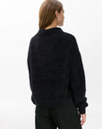 Seen from the back against a white background, a person with straight, light brown hair wears the Rag & Bone jada brushed cashmere sweater in an oversized fit with dark pants.