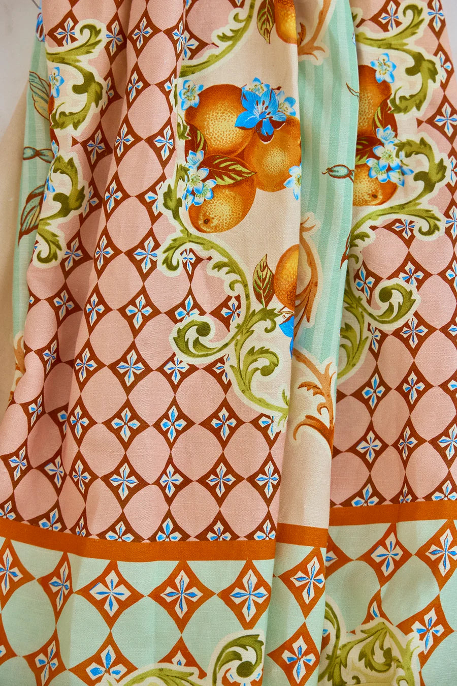 The Tatum Skirt from Hunter Bell NYC features the Gasparilla Gardens print: ornate patterns with orange-hued diamonds on a peach background, golden oranges with blue flowers, and swirling green vines.