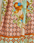 The Tatum Skirt from Hunter Bell NYC features the Gasparilla Gardens print: ornate patterns with orange-hued diamonds on a peach background, golden oranges with blue flowers, and swirling green vines.