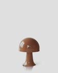 The Julio Portable Table Lamp by Abigail Ahern, in sepia, features a glossy mushroom shape with an integrated LED bulb, set against a plain light gray background.