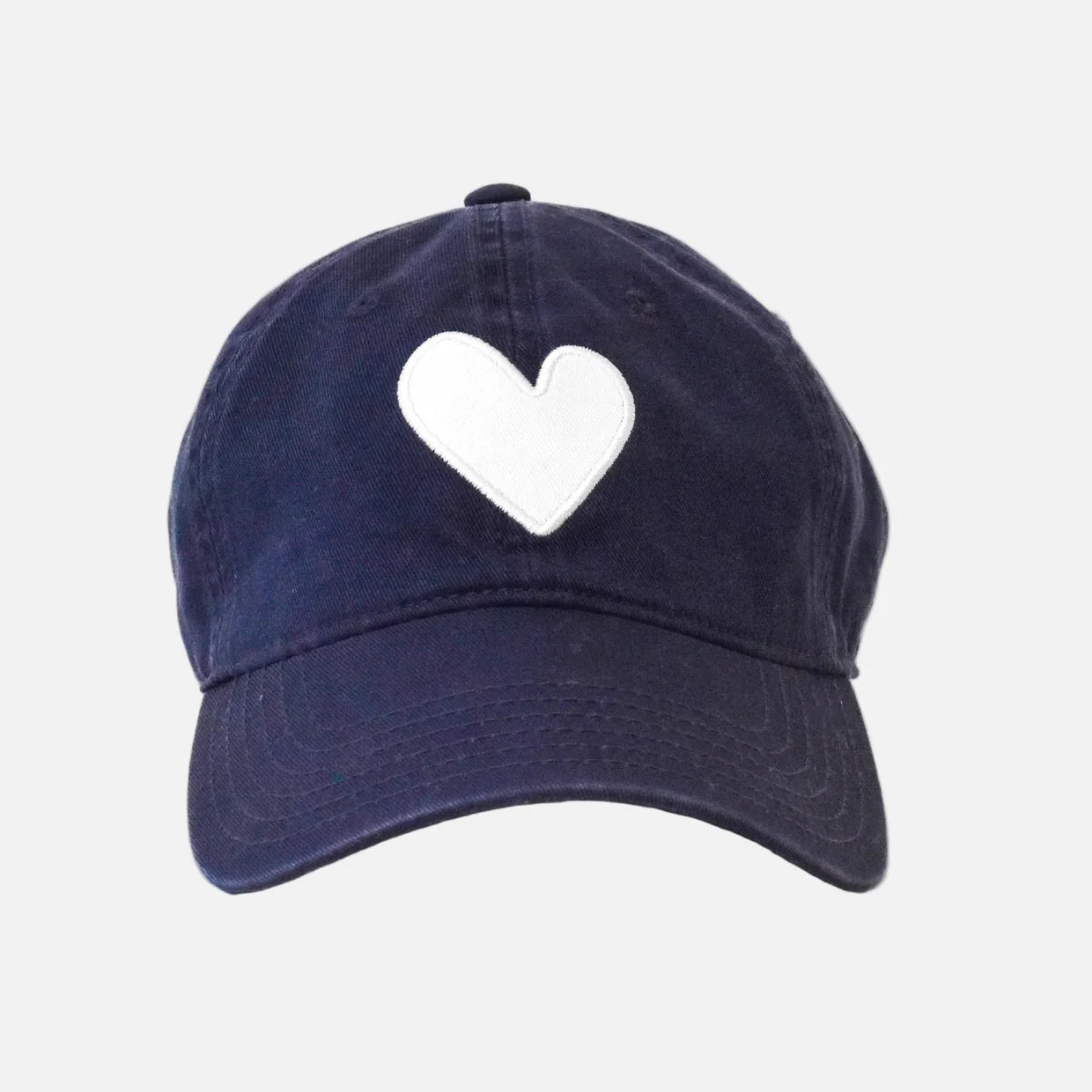 The KR Imperfect Heart Hat by Kerri Rosenthal is a navy blue baseball cap featuring a large embroidered heart patch on the front, displayed against a plain white background.