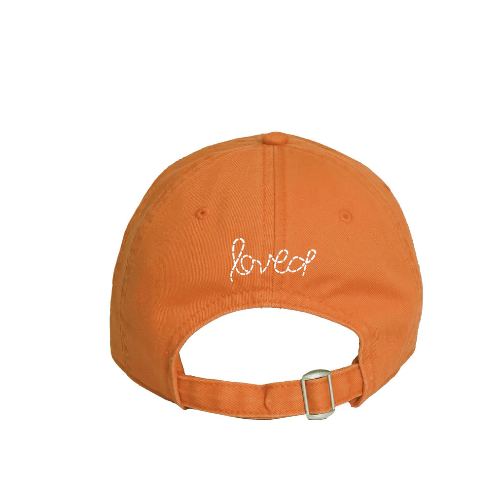 The back of the orange Texas Baseball Hat Heart Patch from Kerri Rosenthal's KR CAP-Sule Collection features "loved" embroidered in white and has an adjustable strap with a metal buckle.