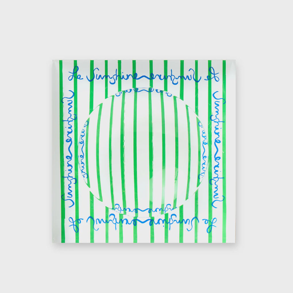 A Kerri Rosenthal 'Le Sunshine Stripe Decorative Bowl', featuring green vertical stripes and blue cursive text on a white ceramic base, is displayed against a plain white background. Its vibrant symmetry adds charm to any coffee table display.