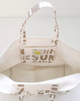 The KR Sunshine Tote by Kerri Rosenthal is a white cotton canvas bag with beige handles and trim, featuring bold "SUN" lettering and Kerri’s Sunshine Artwork, shown open and empty from above on a white background.