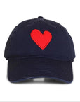 The Kerri Rosenthal Baseball Hat Heart Patch features a navy blue design with a red embroidered heart on the front, shown against a white background—ideal for trendy style enthusiasts.