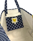 The KR Heart in Check Tote by Kerri Rosenthal features blue and white houndstooth cotton canvas, a small inner pocket with a yellow Drippy Hearts logo, a “Kerri Rosenthal” label, and cream-colored lining.
