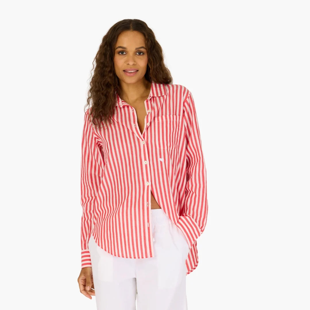 A woman with long curly hair wears the Kerri Rosenthal Mia Stripe Shirt in red and white stripes, paired with white pants, standing against a plain white background.