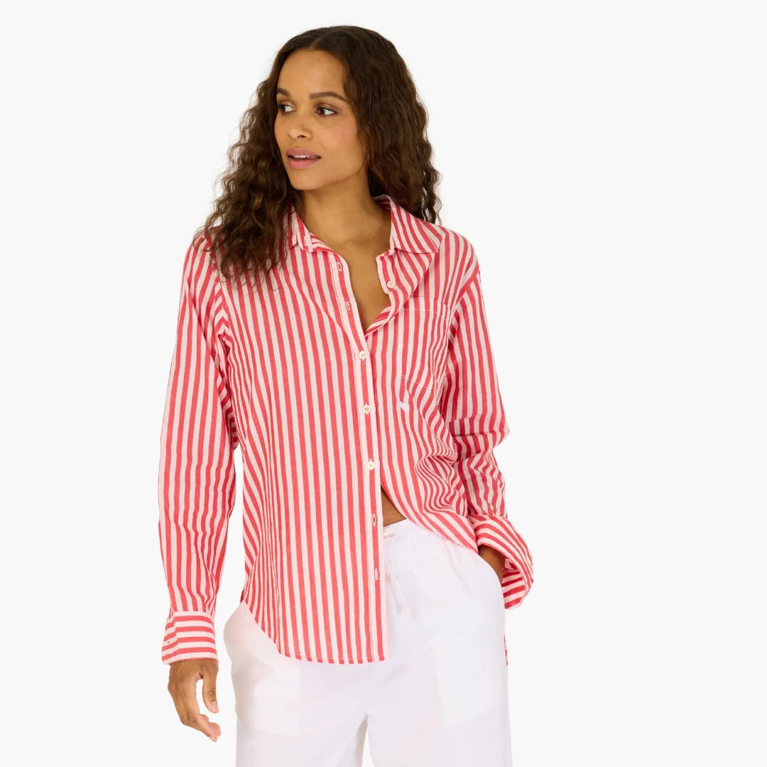 A woman in the Kerri Rosenthal Mia Stripe Shirt—a long-sleeve, red-and-white striped cotton top—paired with white pants stands looking to the side against a plain white background.