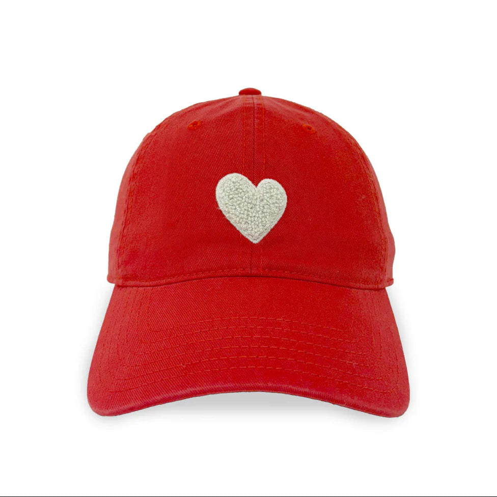 The Embroidered Heart Hat by Kerri Rosenthal is a red cap from our collegiate collection, featuring a white embroidered heart on the front, shown against a plain white background.