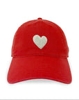 The Embroidered Heart Hat by Kerri Rosenthal is a red cap from our collegiate collection, featuring a white embroidered heart on the front, shown against a plain white background.