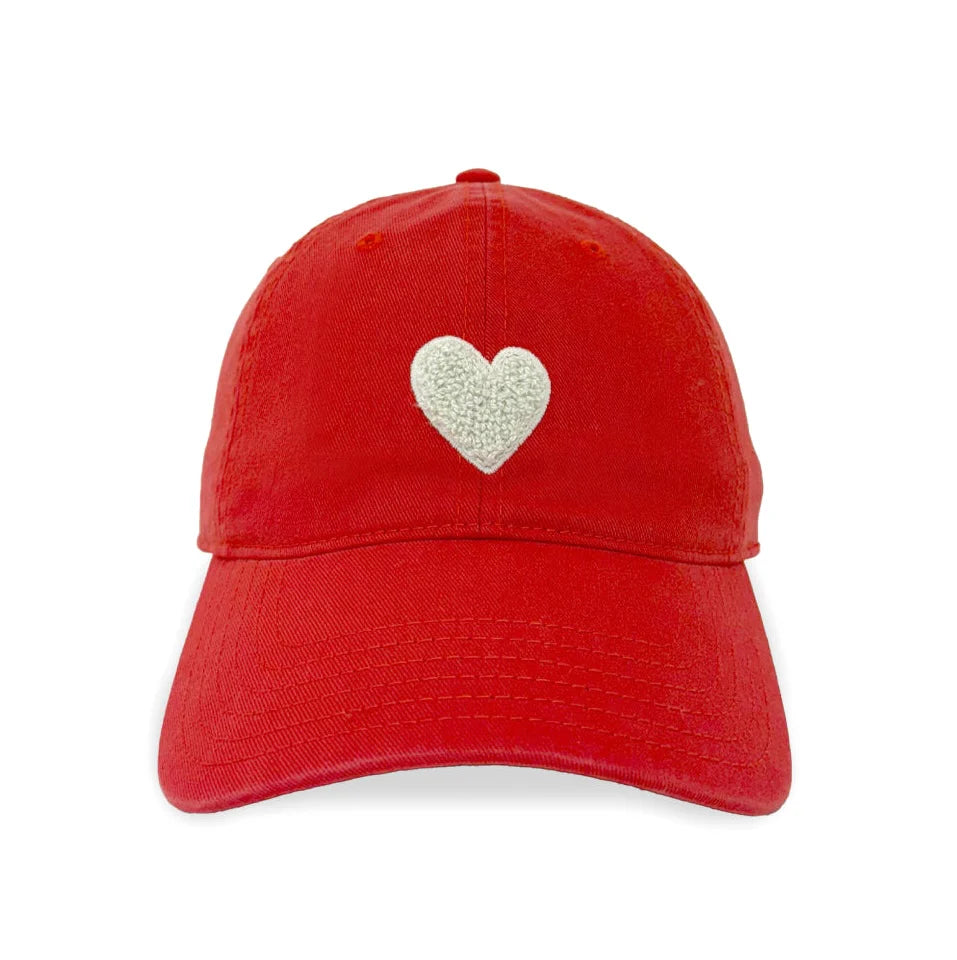 The Kerri Rosenthal Baseball Hat Heart Patch is a red cap with a white embroidered heart on the front, blending popular styles for a fresh look, pictured against a plain white background.