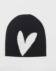 The Kerri Rosenthal Heart Beannie, a stylish cotton cashmere piece, showcases a striking white heart on the front. Displayed flat against a spotless white background, this beanie is ideal when paired with matching mittens and scarf for the perfect cozy outfit.