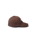 A brown The New York Kap by Kule, featuring a curved brim and adjustable strap at the back, shown in side view against a plain white background.