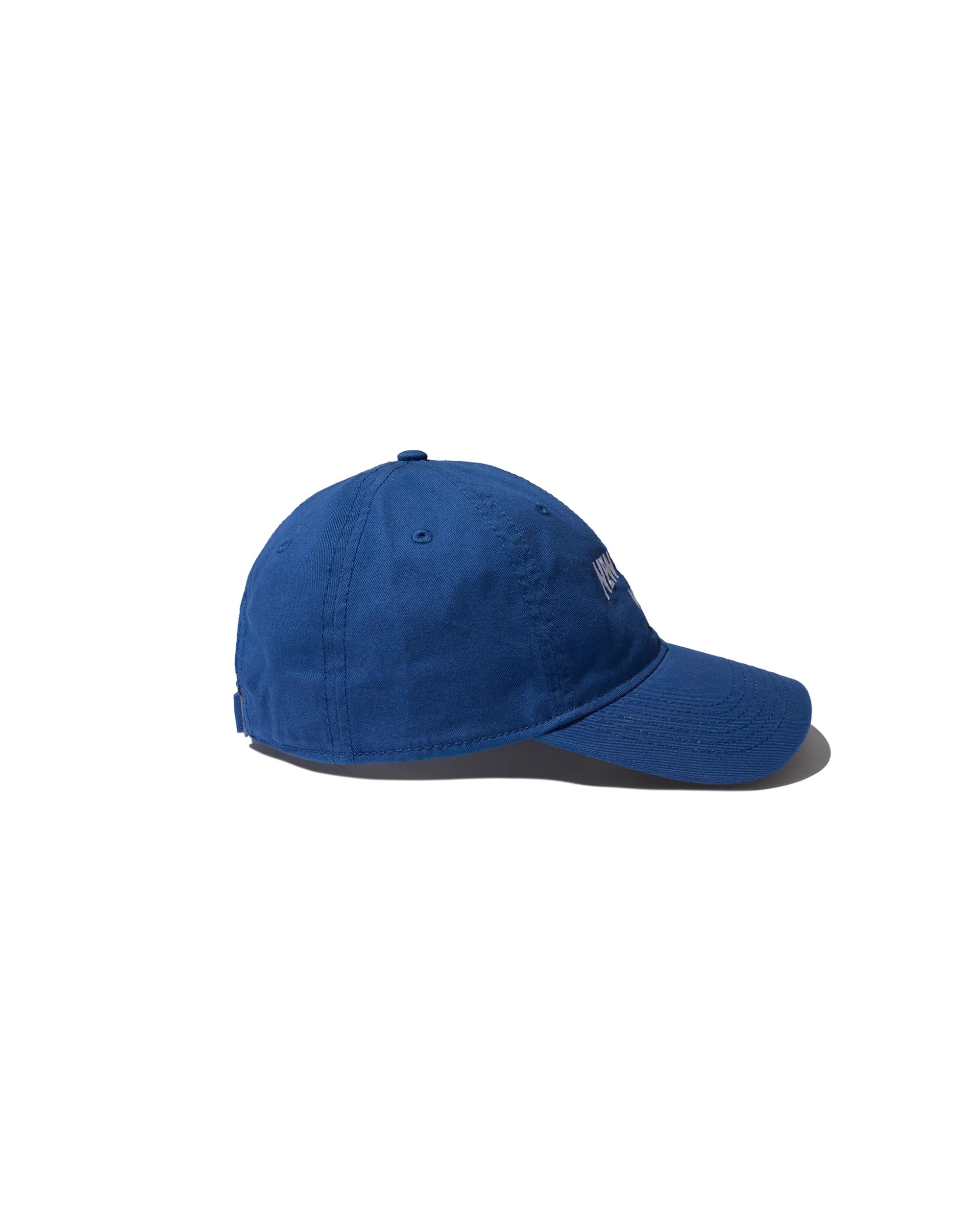 A blue Kule "The New York Kap" is displayed from the side on a white background, featuring a slightly curved brim and visible stitching.