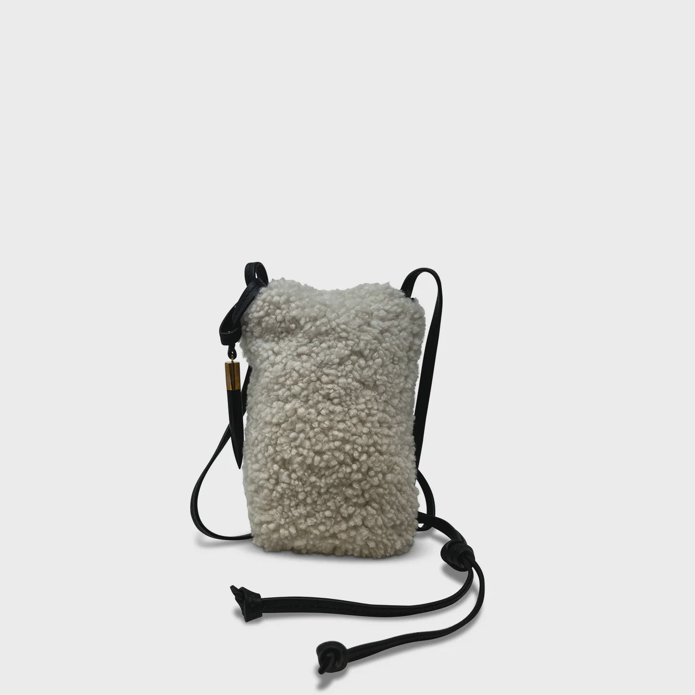 A small Kempton &amp; Co. Mini Sling Bag Natural Shearling featuring textured white material, adjustable black leather straps, and gold accents, is set against a plain white background.