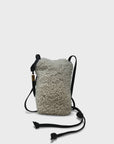 A small Kempton & Co. Mini Sling Bag Natural Shearling featuring textured white material, adjustable black leather straps, and gold accents, is set against a plain white background.