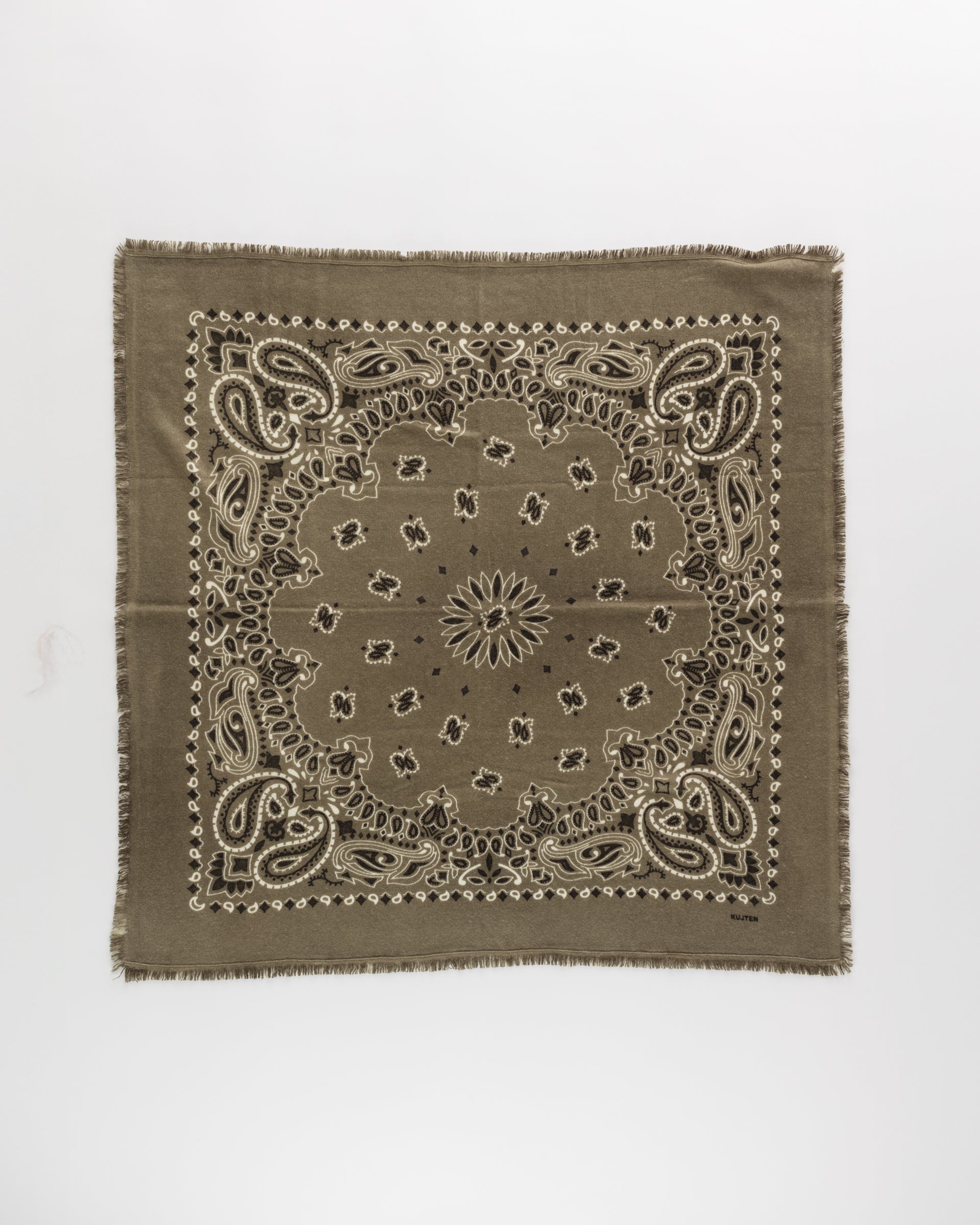The Hachiko Scarf by BCS Group is a square, olive-green bandana made from printed cashmere, featuring a classic white paisley pattern and fringe edges, shown flat on a plain white background.