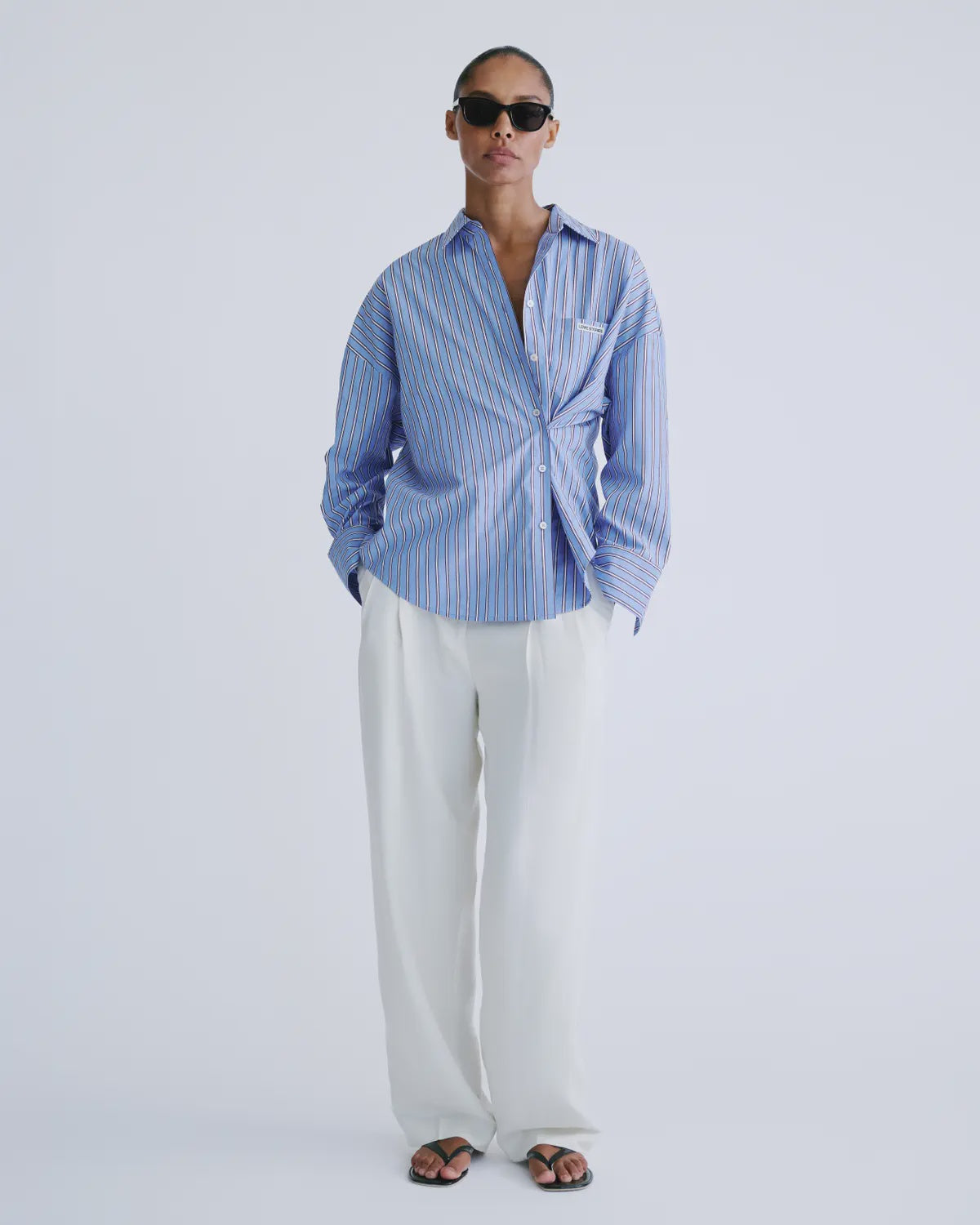 Love Stories HILLARY striped shirt styled with white pants and sandals, relaxed modern look against soft background.