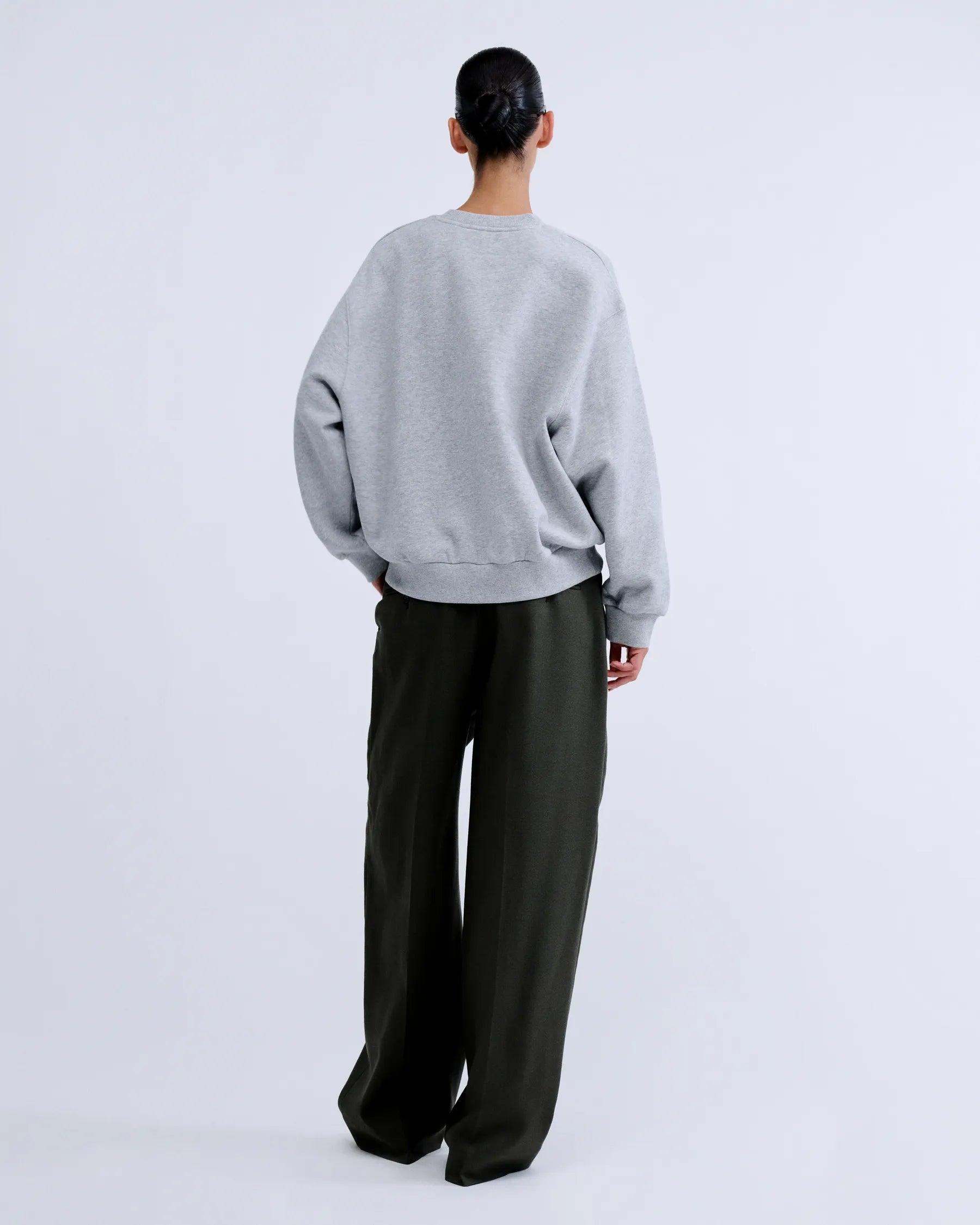 SLOANE Love Stories sweater in dark, relaxed fit, styled with loose pants; minimalist neutral background.