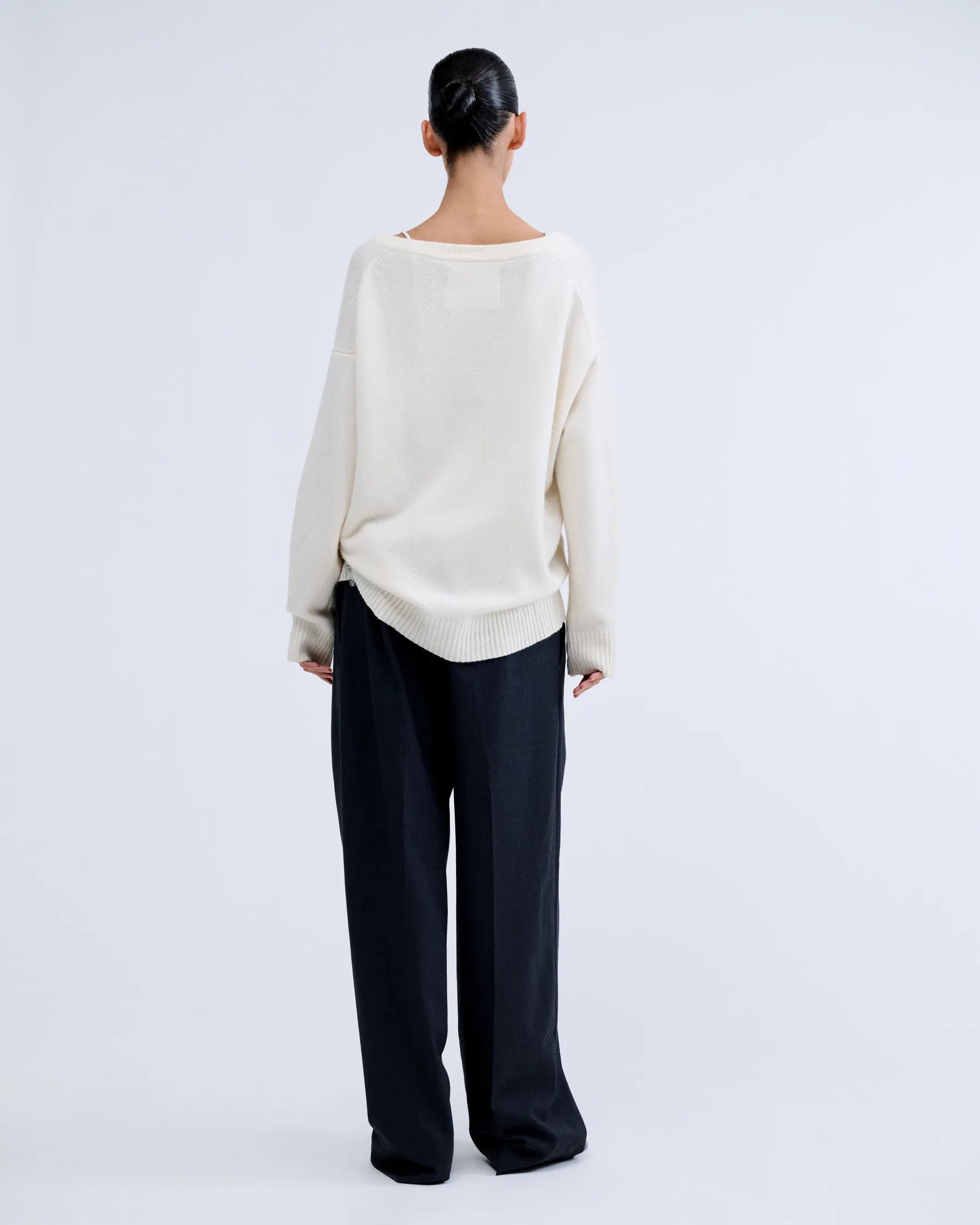 White V-neck wool blend jumper by Love Stories, shown from the back with loose black pants.