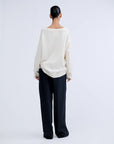 White V-neck wool blend jumper by Love Stories, shown from the back with loose black pants.