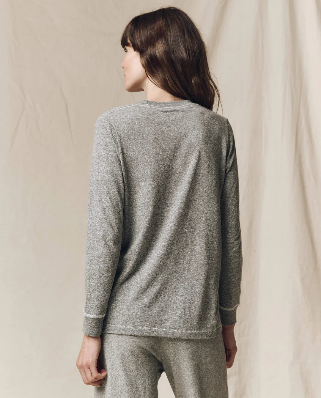 The Great Inc. Long Sleeve Slim Tee in brown, styled with pants, seen from the back.