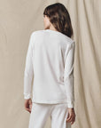 White cotton long sleeve tee by The Great Inc. worn with pants, model facing away, casual style.
