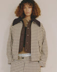 A person with curly brown hair wears the Sea New York Savannah Plaid Jacket and matching pants over a brown vest and shirt, featuring a visible waistband and relaxed fit, standing against a plain light background.