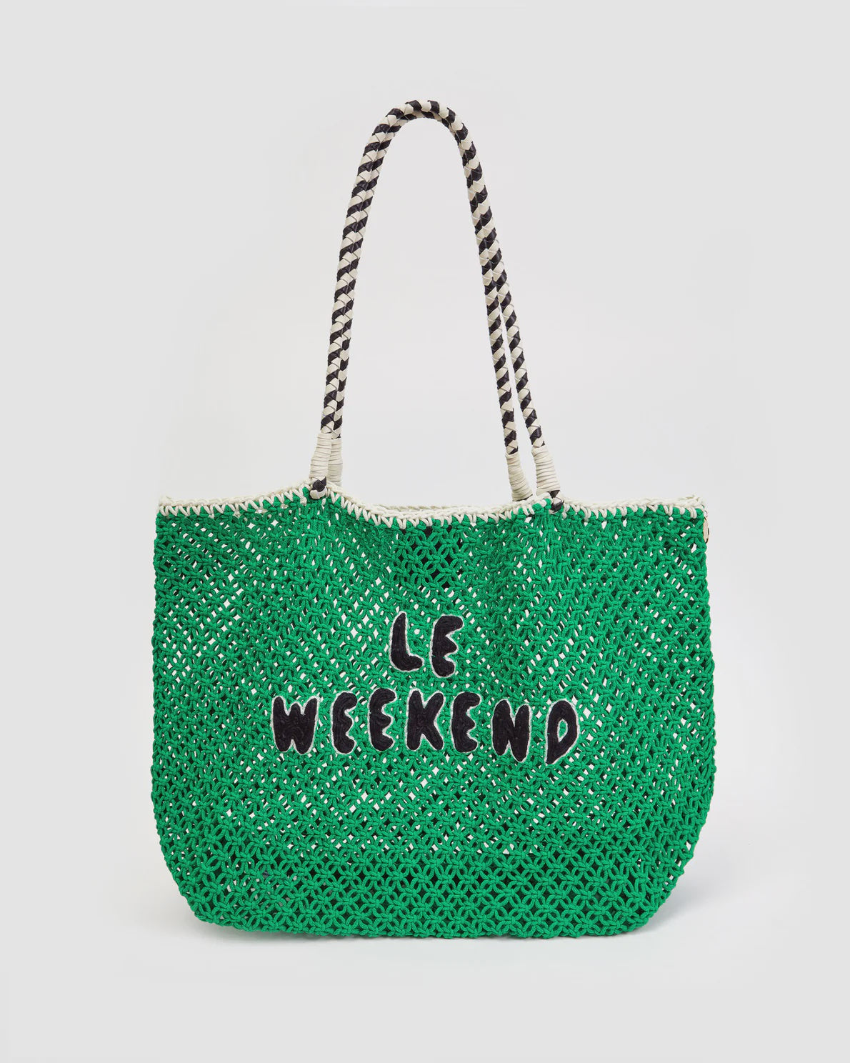 A green woven Lete Tote from Clare Vivier with black and white striped handles, perfect for a summer outing. The bag features the phrase "LE WEEKEND" in black, embroidered letters on the front, offering a chic look against the white background. Crafted with attention to detail, it’s ideal for your weekend adventures.