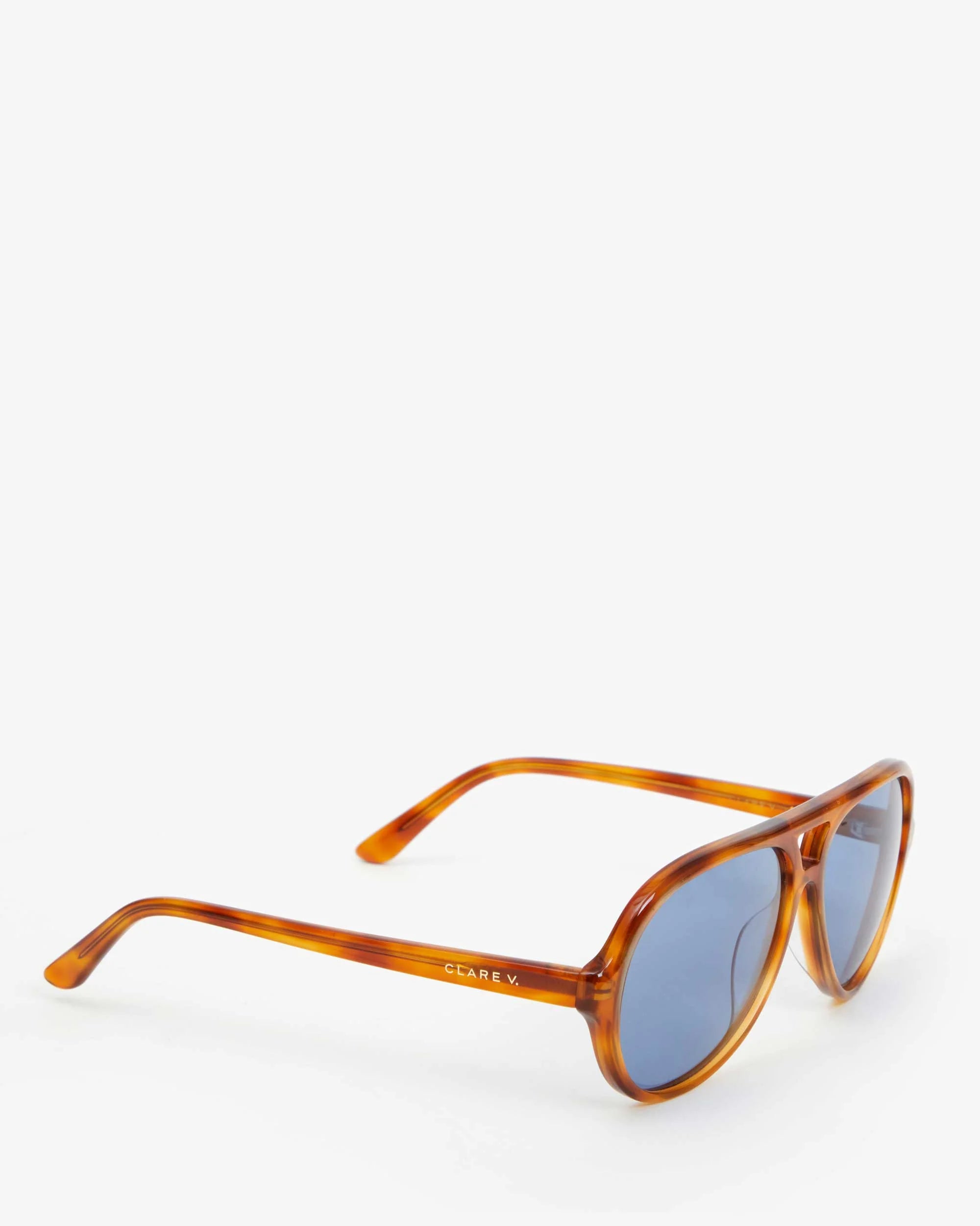 The Lizzie Sunglasses, designed by Clare Vivier, are showcased on a white background. Made from recycled bio-based materials, these environmentally friendly sunglasses come in a brown tortoiseshell frame with blue-tinted lenses. The arm features the brand name &quot;CÉLINE V.&quot; and provides essential UVA/UVB protection.