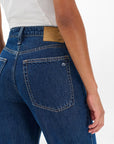Someone is shown from the back wearing Rag & Bone ftwt logan mr wide leg high-waisted dark indigo jeans with visible back pockets and a brown leather patch on the waistband, paired with a partially visible white shirt.