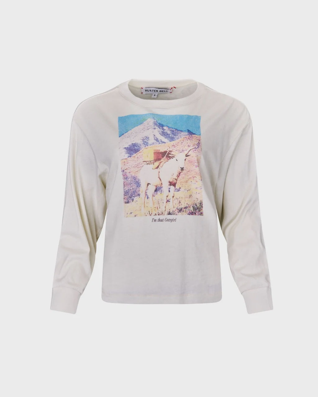 The I'm That Cowgirl LS Tee by Hunter Bell NYC features a fun goat graphic with gear before a mountain and "I'm that Guapito!" printed below, perfect for adventurous cowgirls.