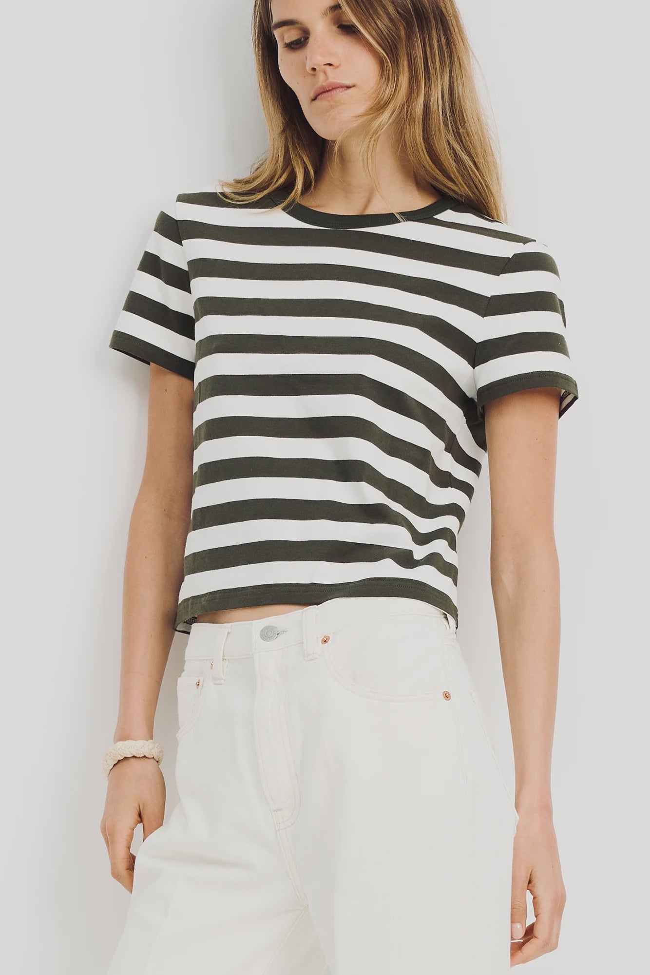 A woman in the Denimist STRIPED BABY T and high-waisted white jeans stands against a plain light background.
