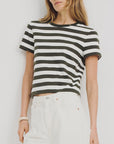 A woman in the Denimist STRIPED BABY T and high-waisted white jeans stands against a plain light background.