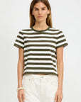 A woman with straight brown hair models the Denimist STRIPED BABY T, a short-sleeved black and white crewneck tee, paired with high-waisted white pants against a plain white background.